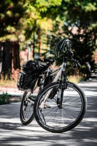 A mountain bike parked on a shaded forest path with a helmet and panniers for rental on the Katy Trail